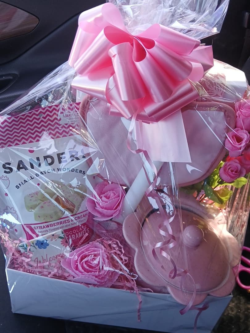 Pink celebration gift with a satin bow, sweets, and a flower-shaped dish